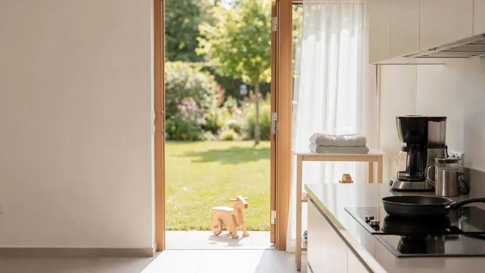 Helle Wohnküche mit offener Terrassentür und Blick in einen sonnigen Garten